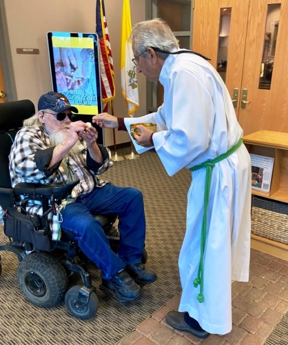 Acolyte Rod McNeil serves Life Safety Team Member Mack McGuire the Eucharist.